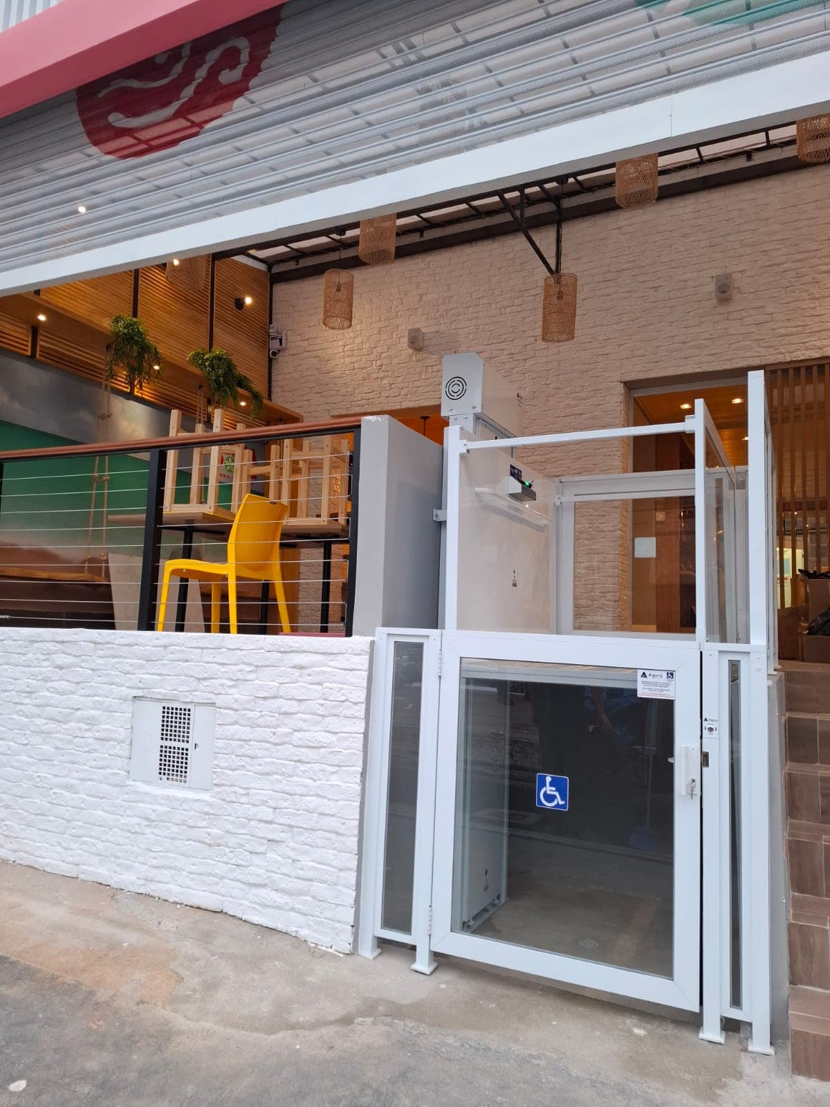 Plataforma comercial branca com portão e guarda corpo instalada na entrada de uma loja