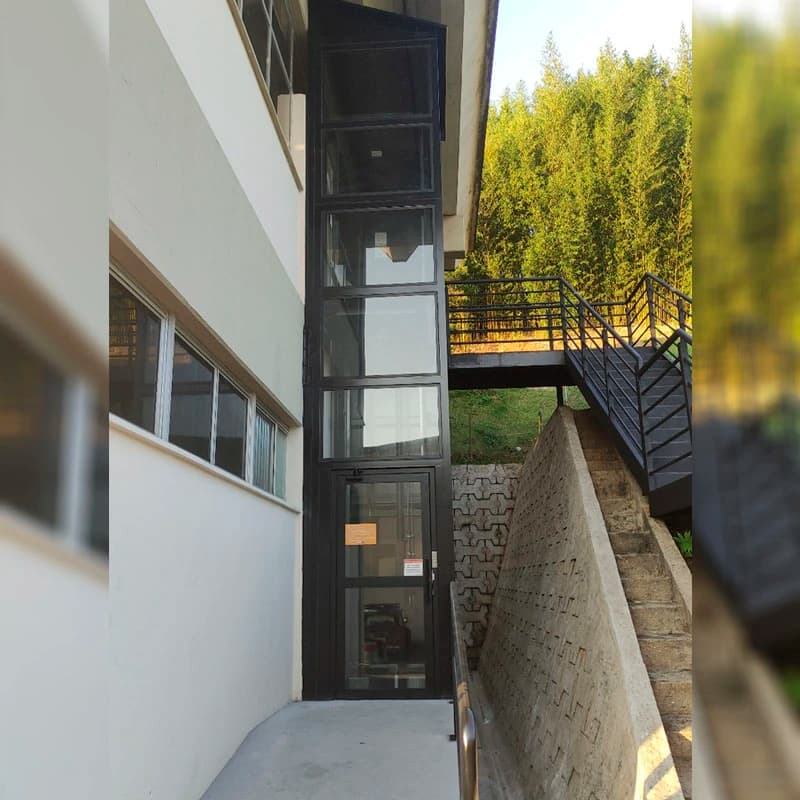 Elevador hidráulico enclausurado em vidro instalado em fachada externa de várias paradas